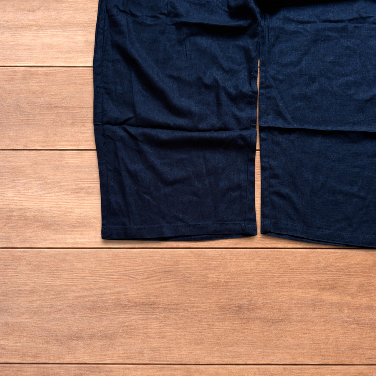 Vintage linen style black baggy wide leg trousers laid flat on wooden background.