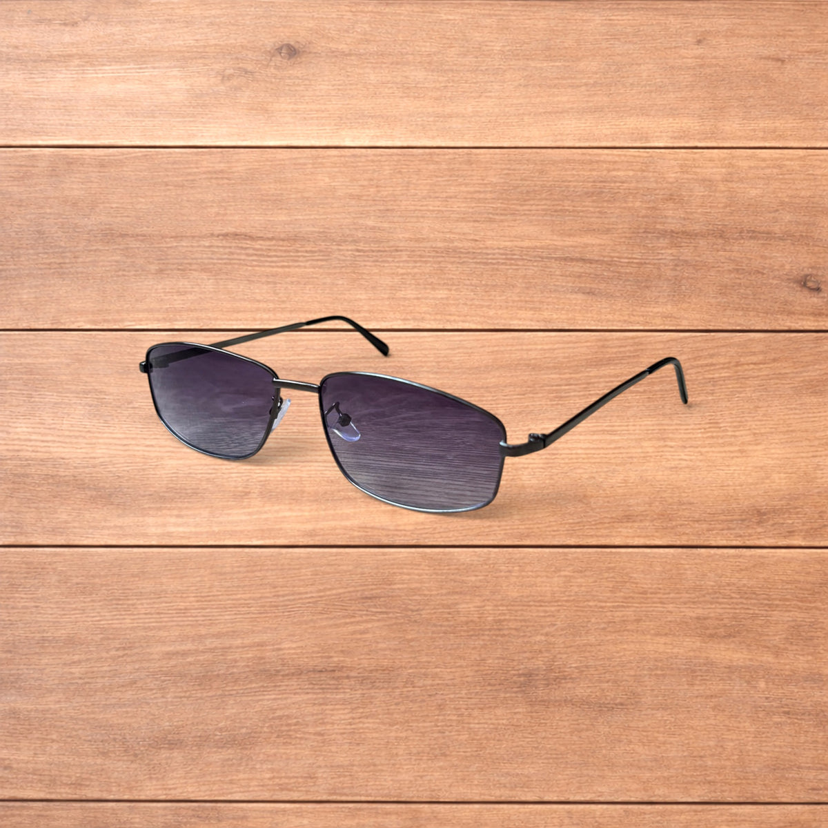 Hand holding vintage style black metal frame sunglasses with purple lenses against a wooden background.