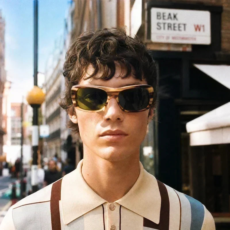 Man on Beak Street in striped polo and sunglasses.