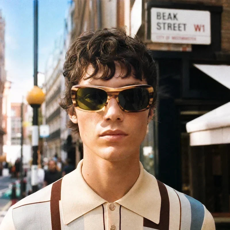 Man on Beak Street in striped polo and sunglasses.