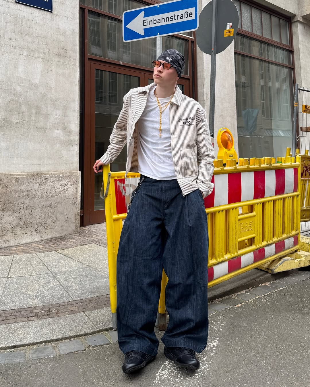 Man posing in street with baggy jeans and cropped jacket.