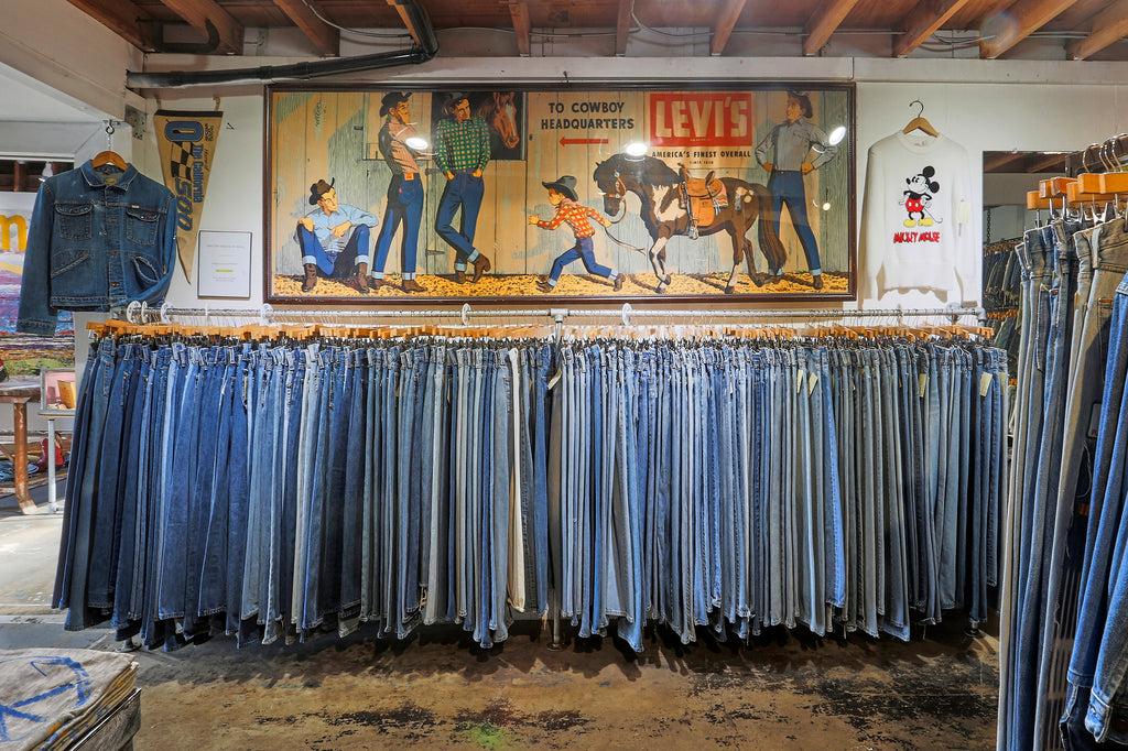 Large rail of vintage blue jeans beneath an old Levi's store sign