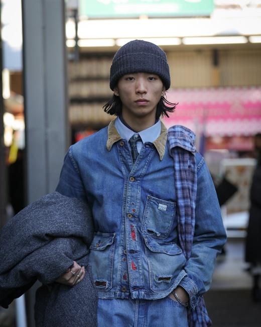 Model wearing a vintage blue denim workwear jacket with a beanie