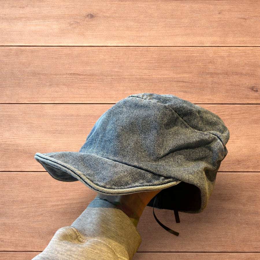 Mid blue denim vintage style newsboy painter flat cap beret held by hand on wooden background