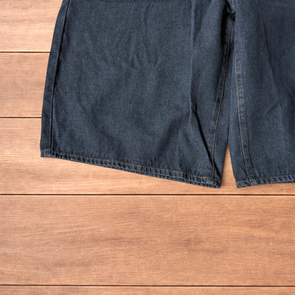 Baggy wide leg denim jorts in washed black with contrast stitching laid flat on wooden surface showing front and back views