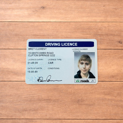 Brett Clement driving licence novelty card with blue header and photo ID, shown front and back and held in hand.