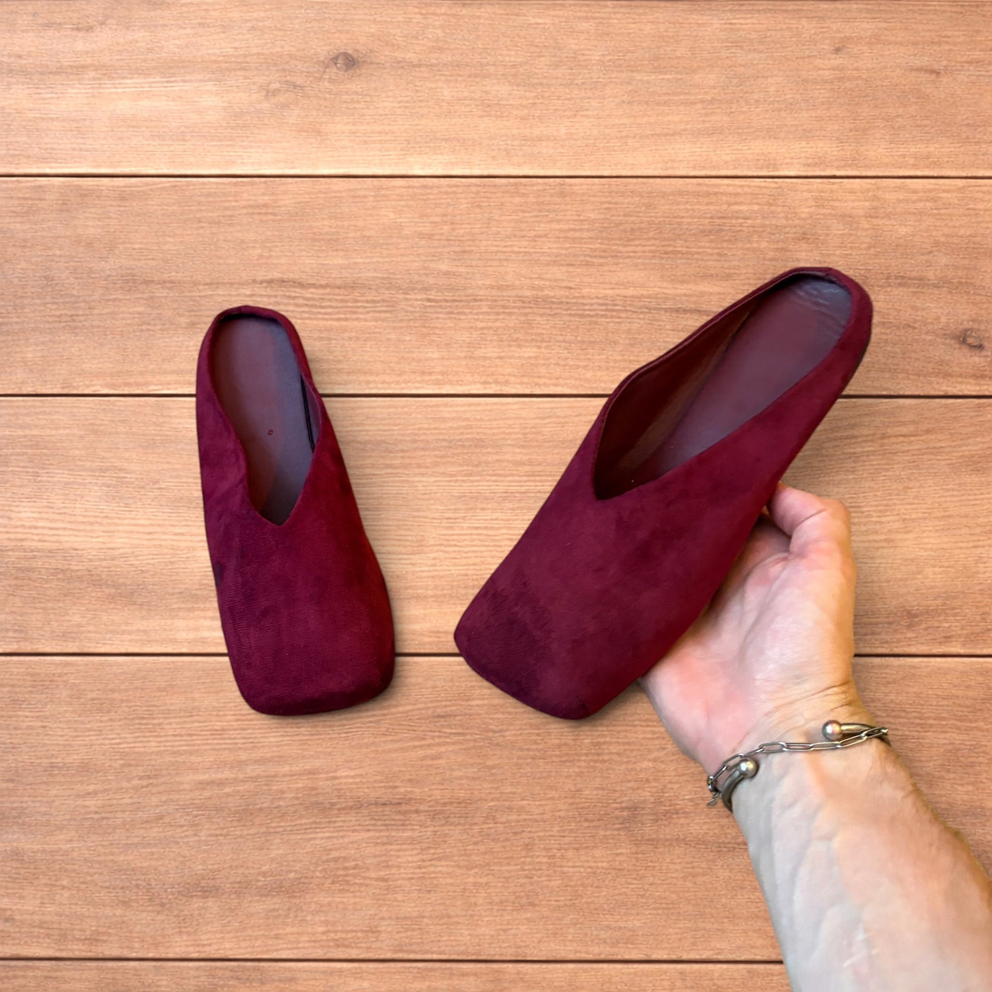 Pair of vintage style red suede flat top square toe slip-on shoes on wooden floor