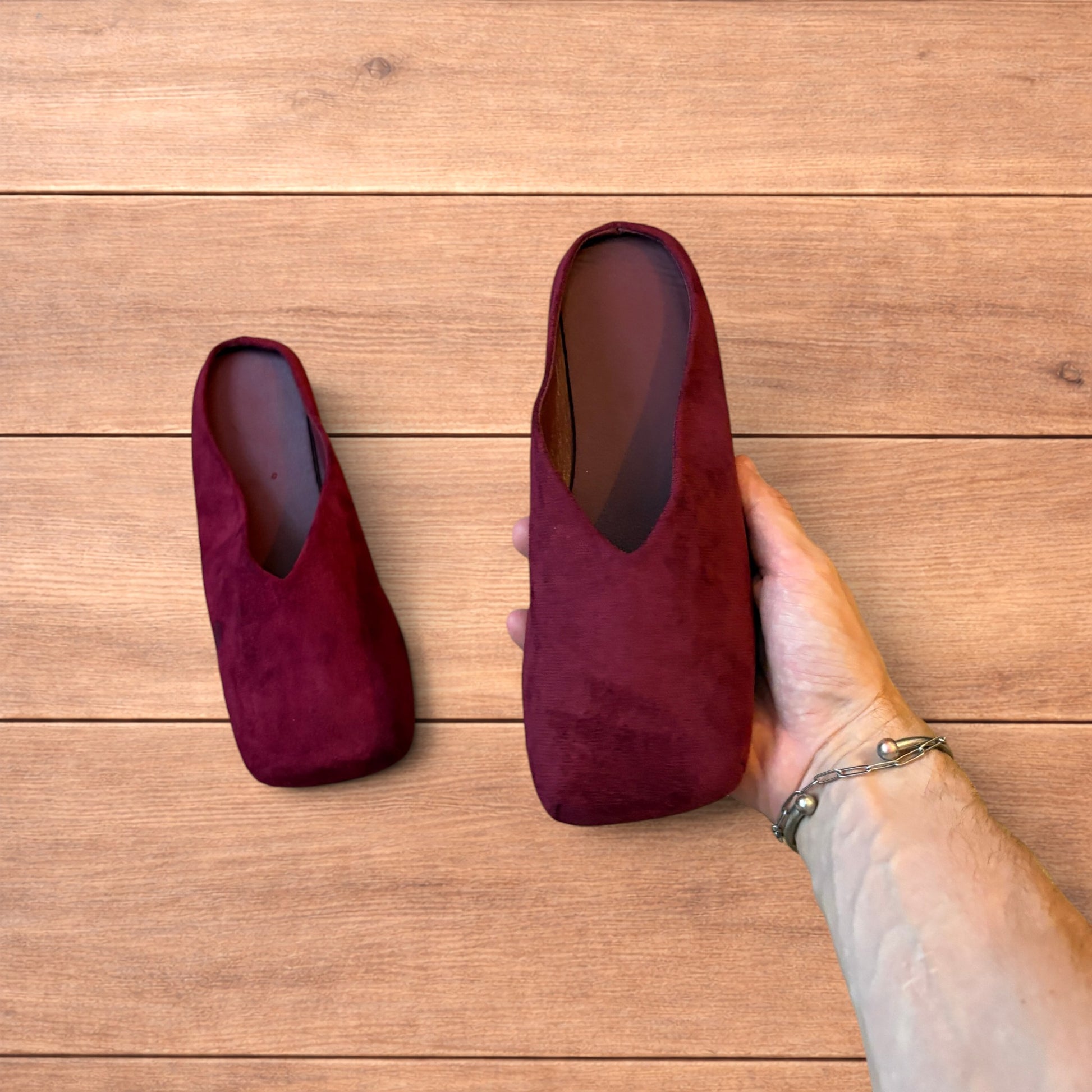 Pair of vintage style red suede flat top square toe slip-on shoes on wooden floor