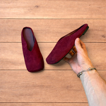 Pair of vintage style red suede flat top square toe slip-on shoes on wooden floor