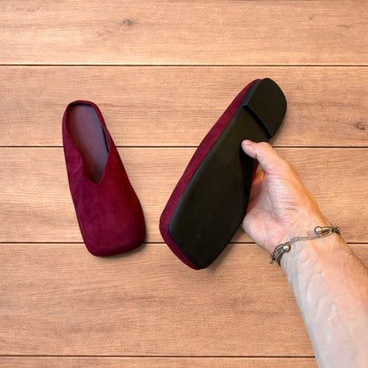 Pair of vintage style red suede flat top square toe slip-on shoes on wooden floor