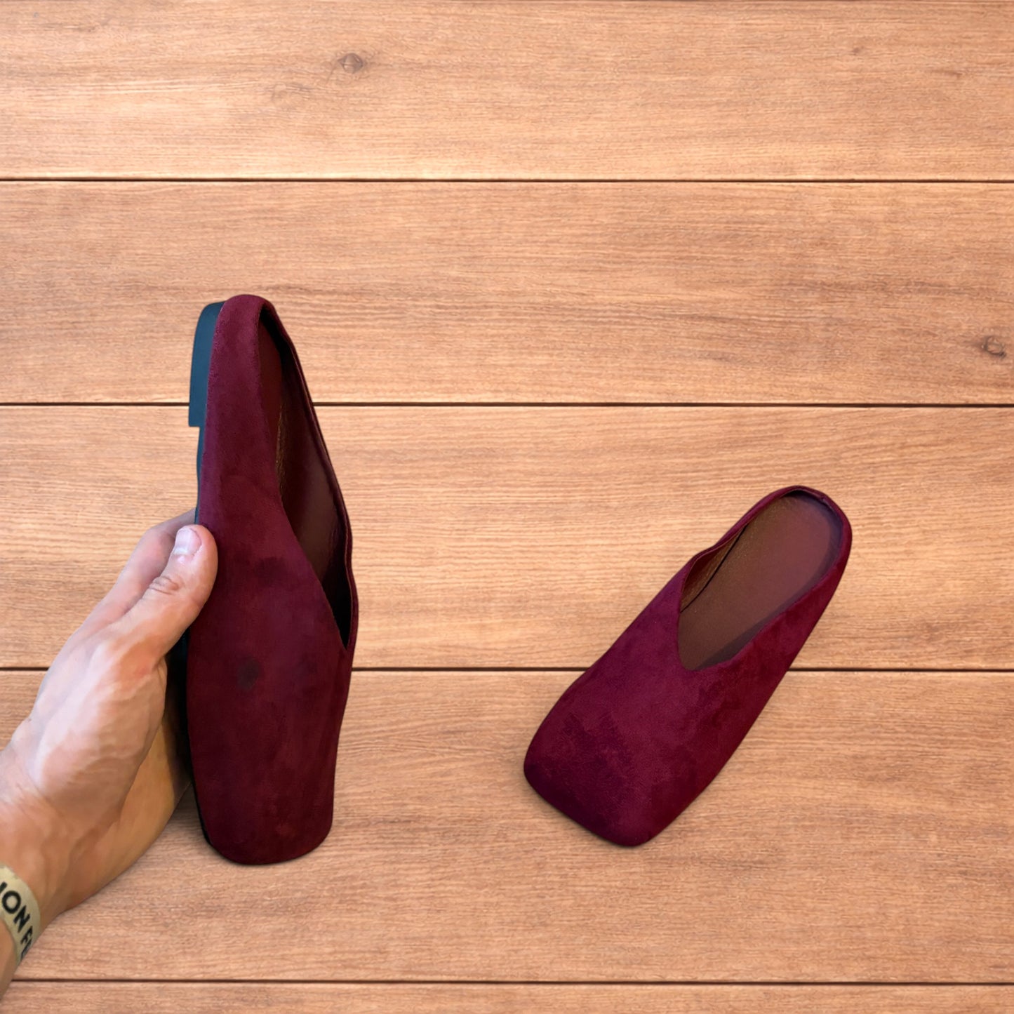 Pair of vintage style red suede flat top square toe slip-on shoes on wooden floor