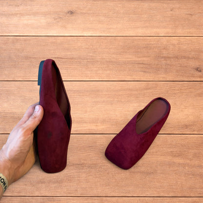 Pair of vintage style red suede flat top square toe slip-on shoes on wooden floor