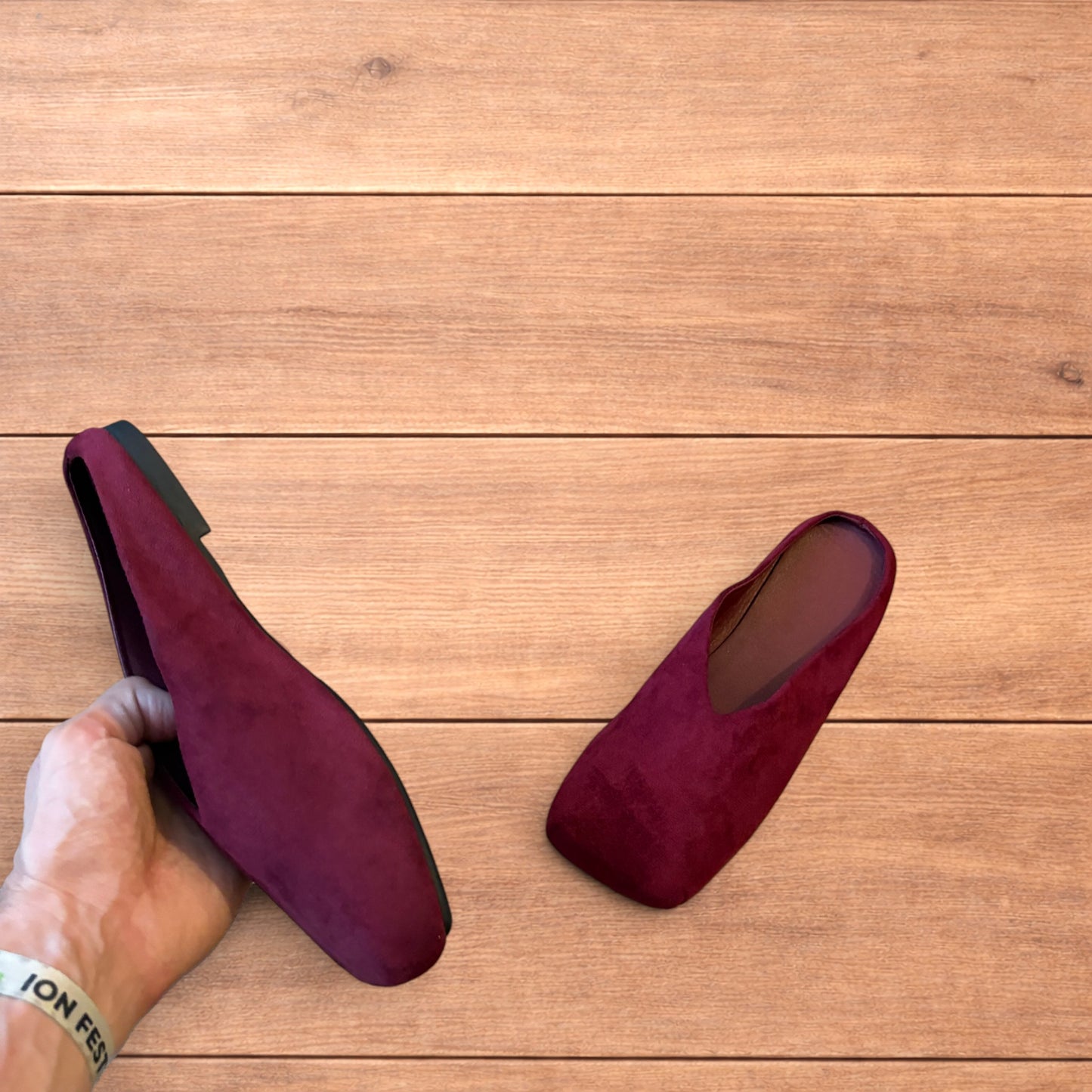 Pair of vintage style red suede flat top square toe slip-on shoes on wooden floor