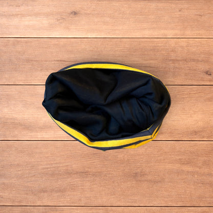 Vintage style striped beanie hat in yellow and black laid flat on wooden surface