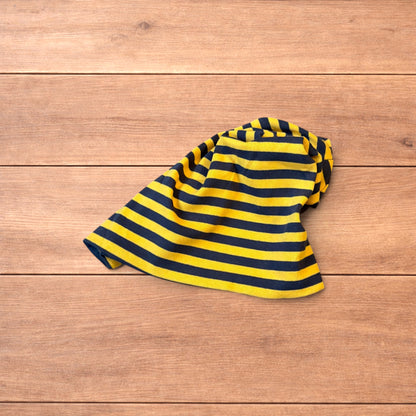 Vintage style striped beanie hat in yellow and black laid flat on wooden surface