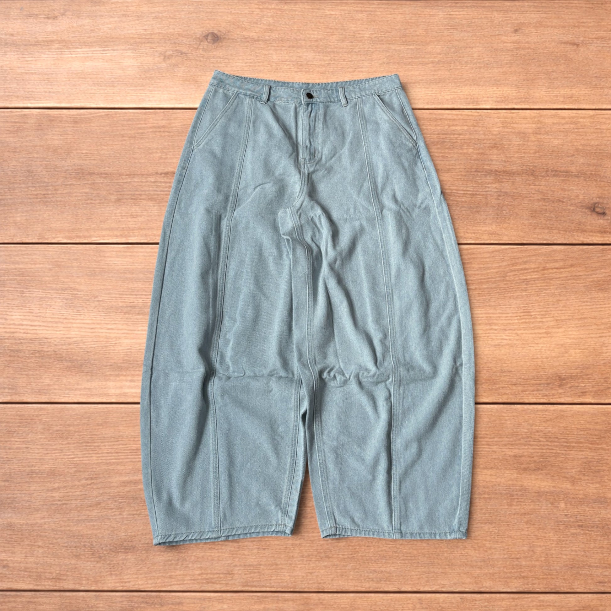 Light blue baggy wide leg vintage style denim jeans laid flat on wood surface showing front and back views
