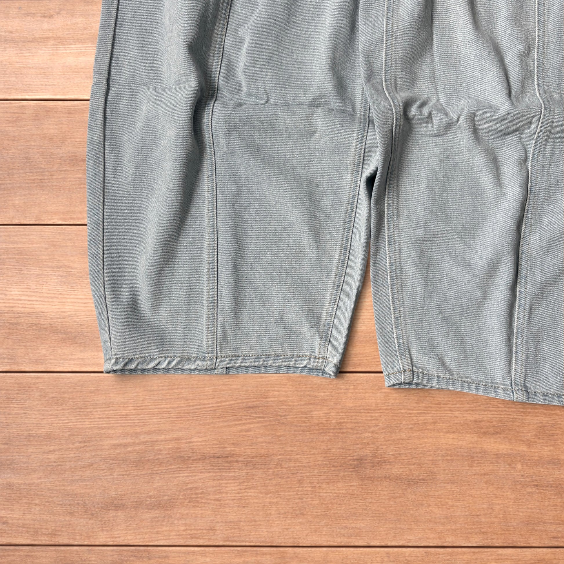 Light blue baggy wide leg vintage style denim jeans laid flat on wood surface showing front and back views