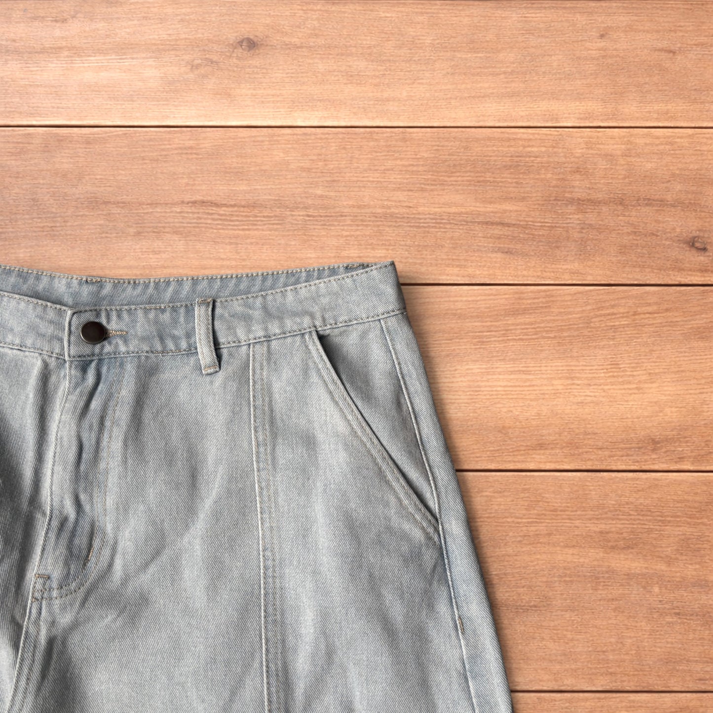 Light blue baggy wide leg vintage style denim jeans laid flat on wood surface showing front and back views