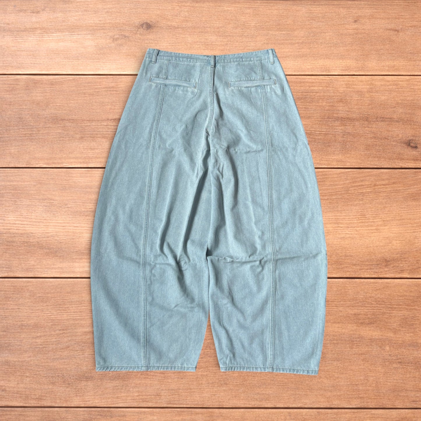 Light blue baggy wide leg vintage style denim jeans laid flat on wood surface showing front and back views