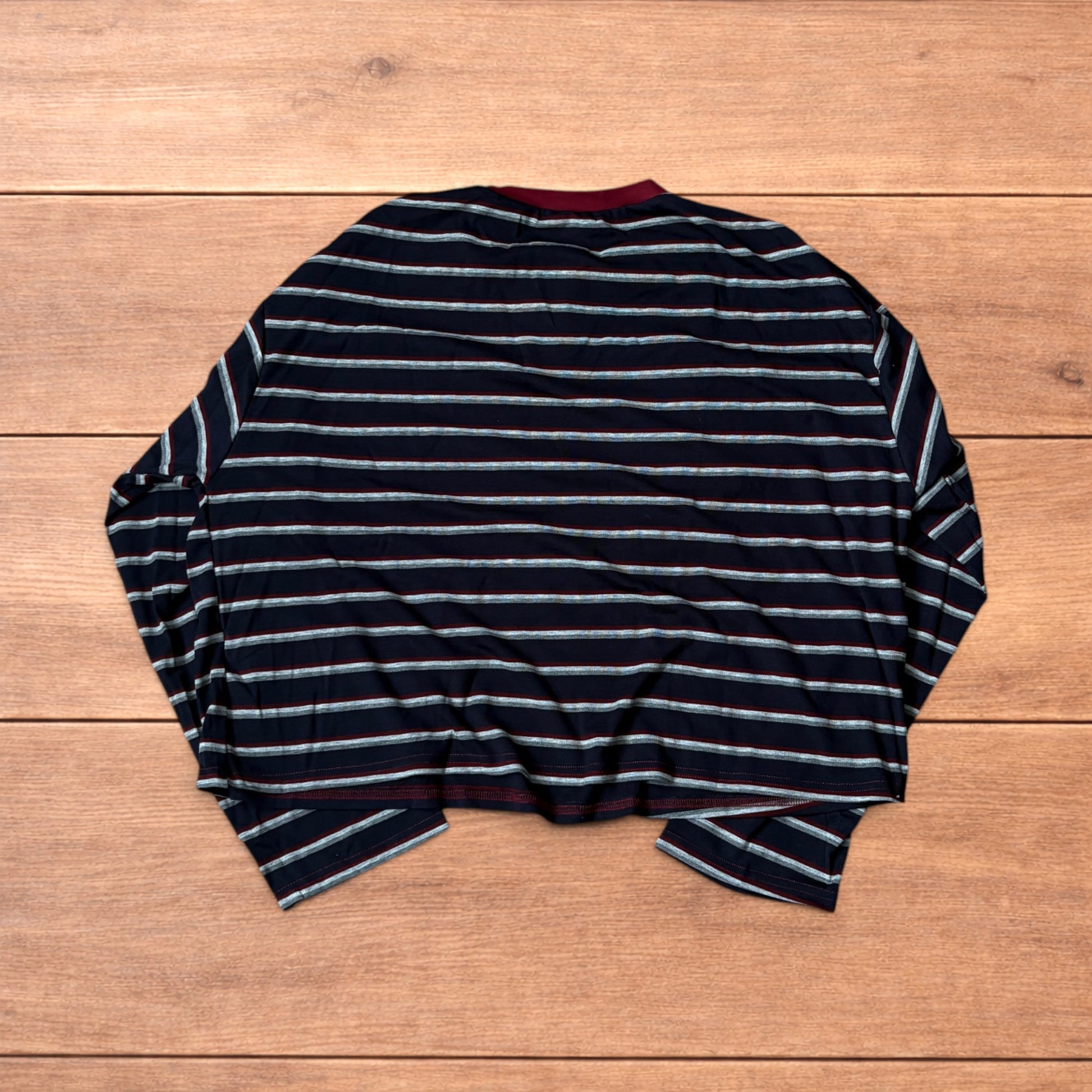 Navy navy blue striped henley long sleeve top with burgundy collar and button placket laid flat on wooden background