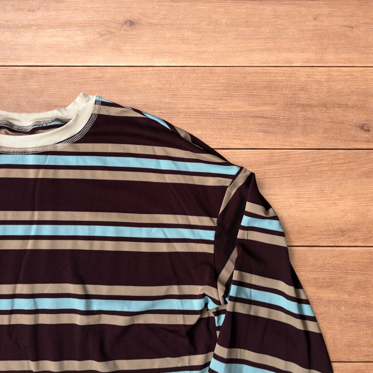 Relaxed fit long sleeve striped t-shirt in brown, blue and beige laid flat on wooden surface