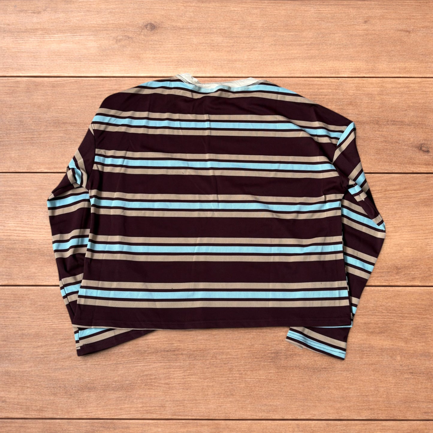 Relaxed fit long sleeve striped t-shirt in brown, blue and beige laid flat on wooden surface