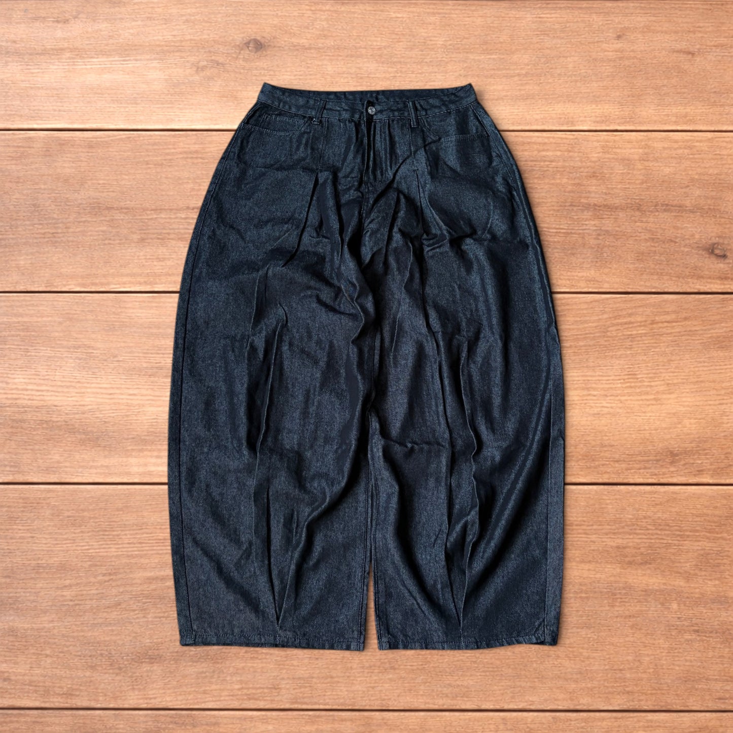 Dark grey baggy wide leg raw denim jeans laid flat showing front and back pockets and button fly