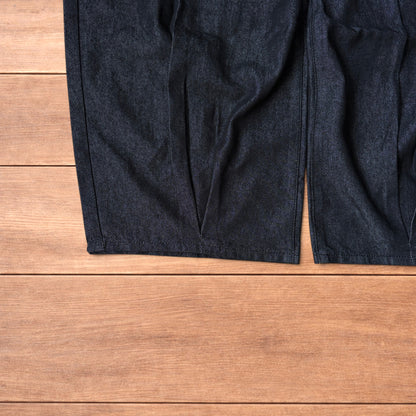 Dark grey baggy wide leg raw denim jeans laid flat showing front and back pockets and button fly