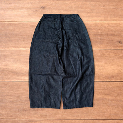 Dark grey baggy wide leg raw denim jeans laid flat showing front and back pockets and button fly