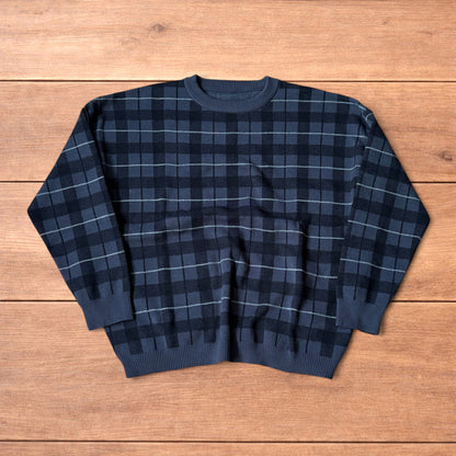 Vintage style checkered pullover jumper in grey black laid flat on wooden surface