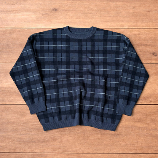 Vintage style checkered pullover jumper in grey black laid flat on wooden surface