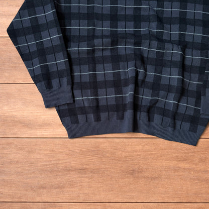 Vintage style checkered pullover jumper in grey black laid flat on wooden surface