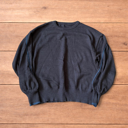 Dark grey vintage style pullover jumper with slim blue piping detail on sleeves laid flat on wooden surface.