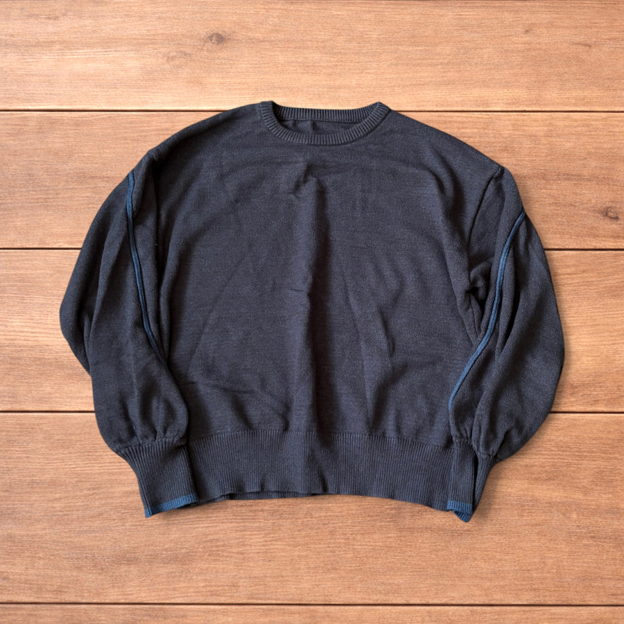 Dark grey vintage style pullover jumper with slim blue piping detail on sleeves laid flat on wooden surface.