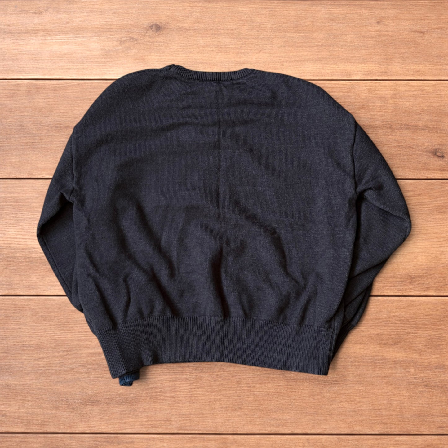 Dark grey vintage style pullover jumper with slim blue piping detail on sleeves laid flat on wooden surface.
