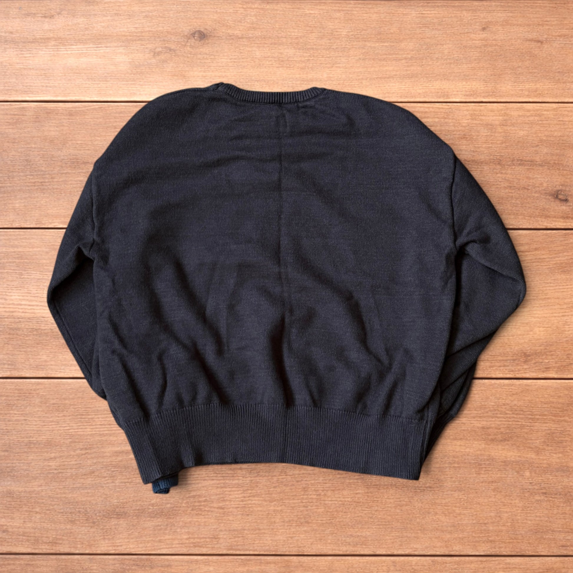 Dark grey vintage style pullover jumper with slim blue piping detail on sleeves laid flat on wooden surface.