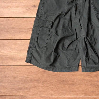 Vintage style baggy cargo shorts in khaki green laid flat on wooden surface showing front and back details.