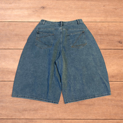 Mid blue baggy wide leg denim jorts shorts with front and back pockets laid flat on wooden background.