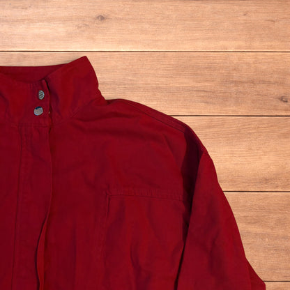 Red vintage style cropped zip up track jacket with high neck and drawstring waist laid flat on wooden surface.