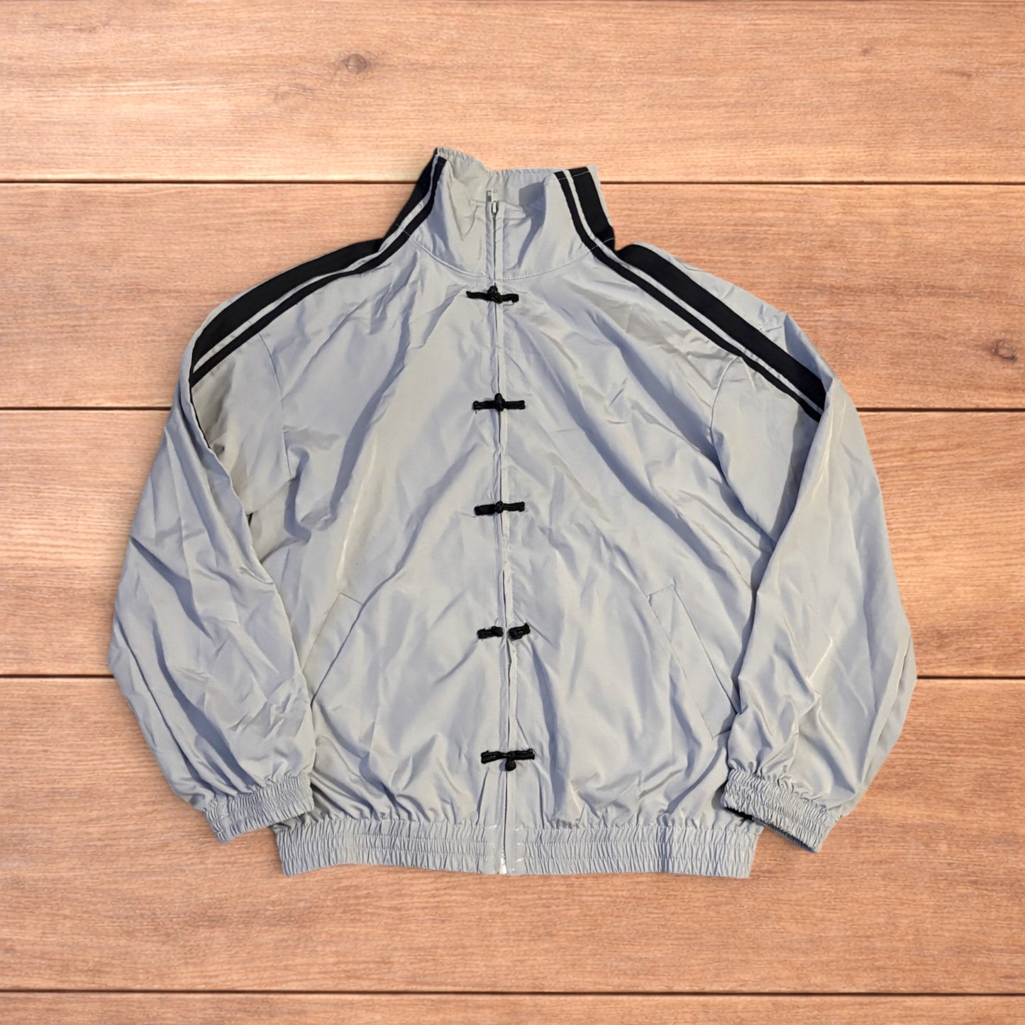 Light blue Japanese style zip up track jacket with black side stripes and toggle fasteners.
