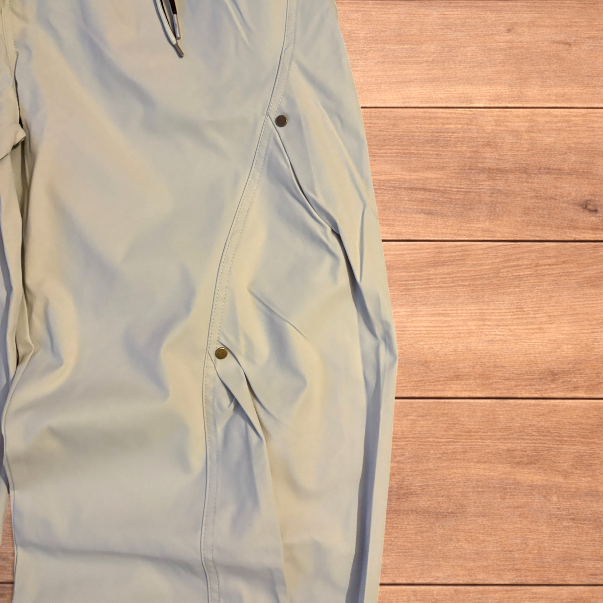 Beige baggy gorpcore hiking pants laid flat showing drawstring waist, toggled hems and back flap pockets.