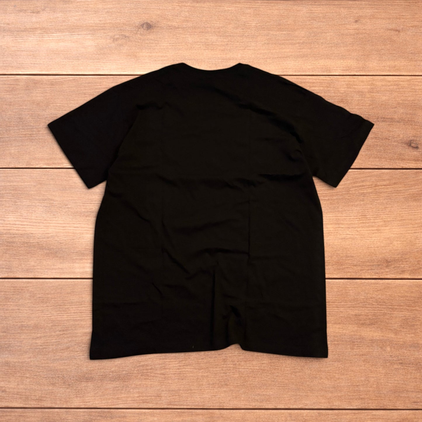 Black Yung Lean 2002 t-shirt with yellow front graphic text laid flat on a wooden surface.