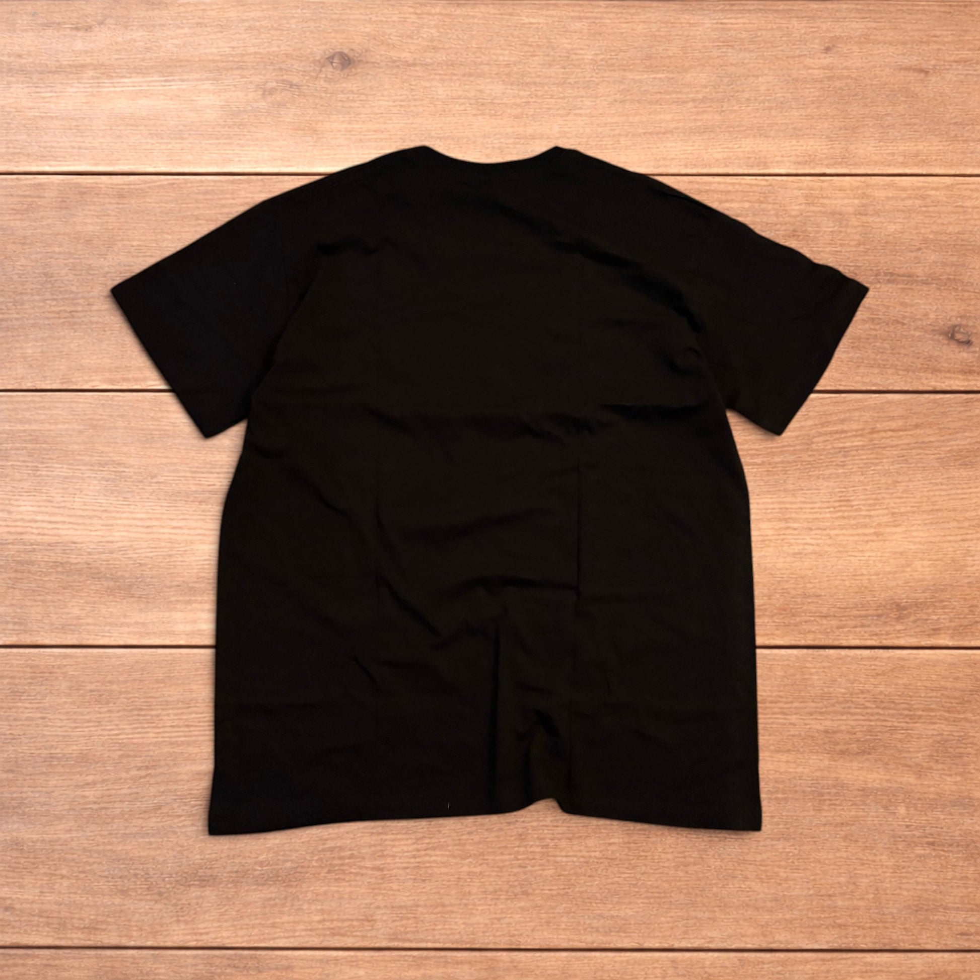 Black Yung Lean 2002 t-shirt with yellow front graphic text laid flat on a wooden surface.