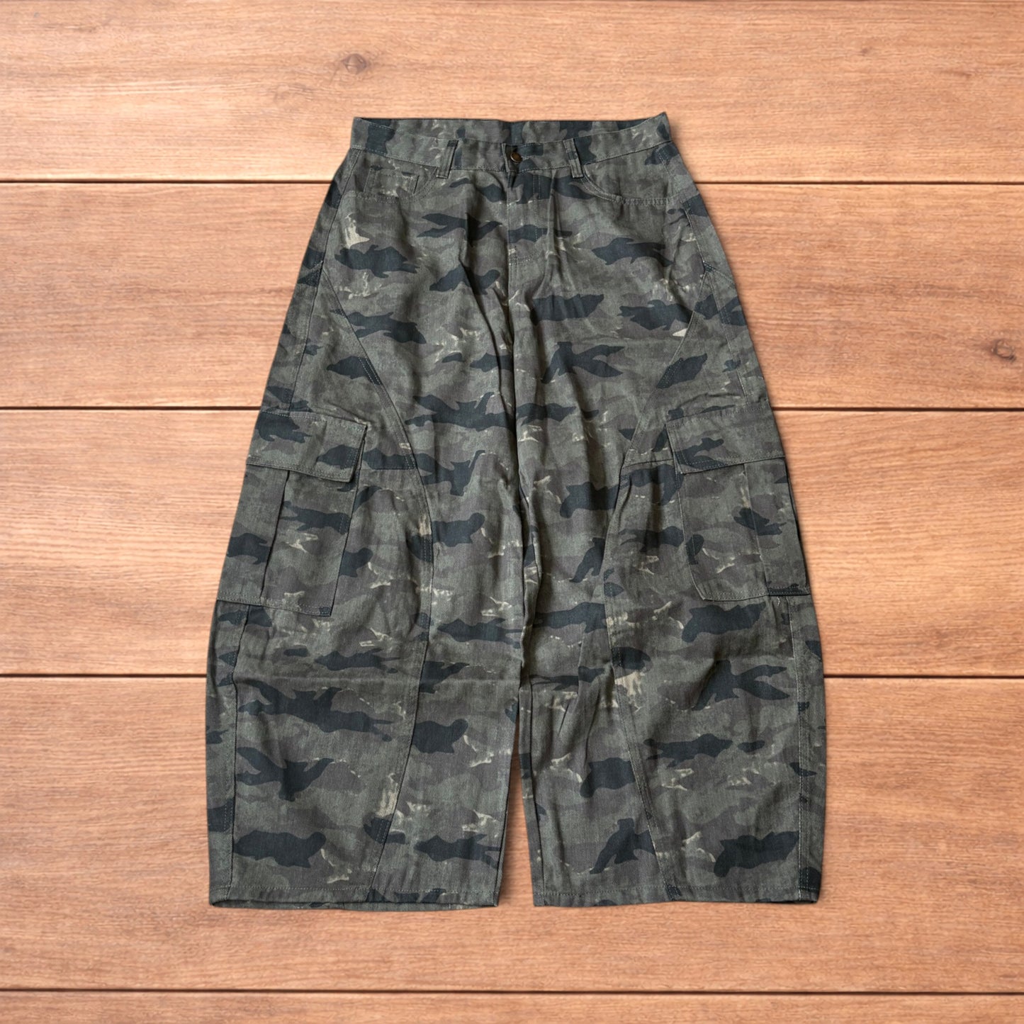 Baggy wide leg cargo trousers in army camo laid flat showing front, back and close-up details on wooden background.