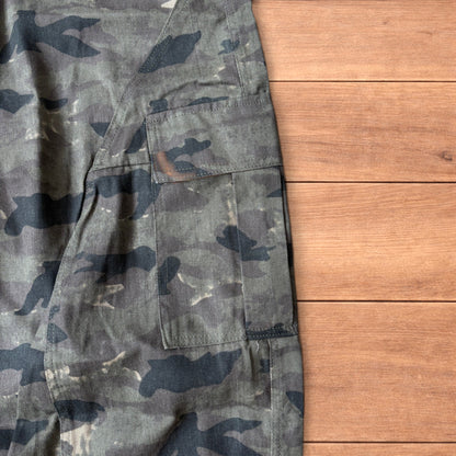 Baggy wide leg cargo trousers in army camo laid flat showing front, back and close-up details on wooden background.
