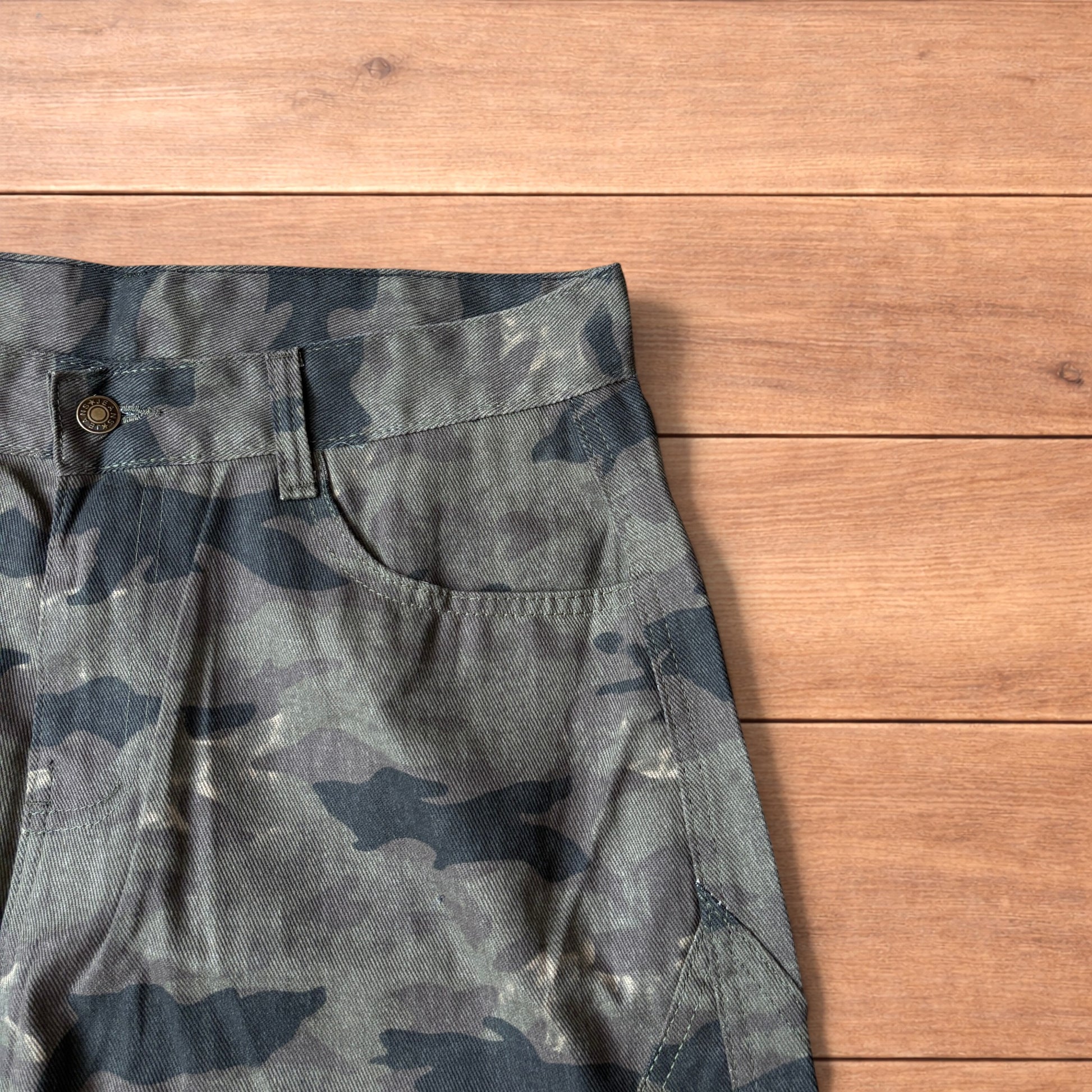 Baggy wide leg cargo trousers in army camo laid flat showing front, back and close-up details on wooden background.