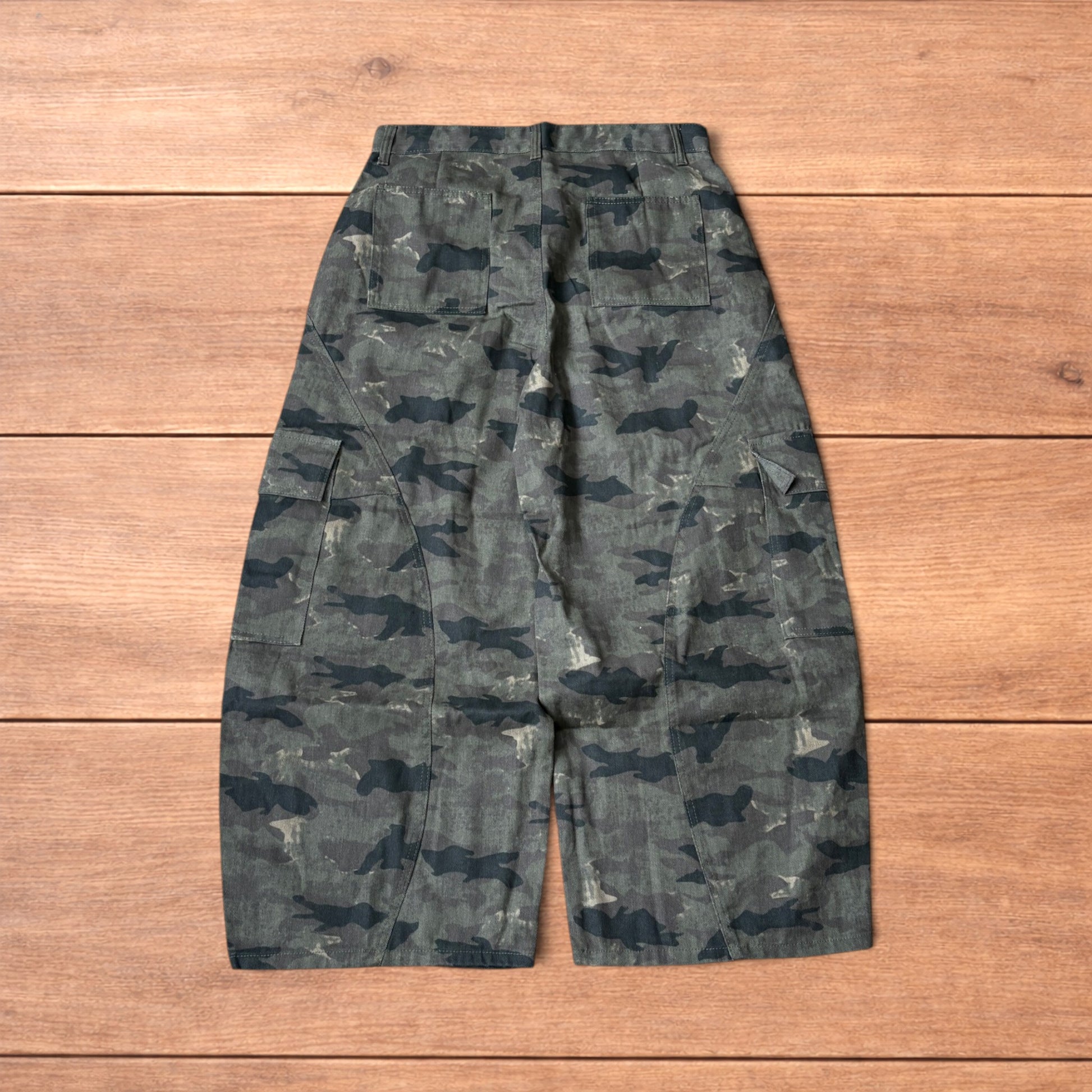 Baggy wide leg cargo trousers in army camo laid flat showing front, back and close-up details on wooden background.