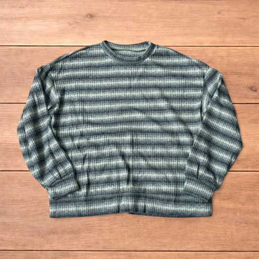 Vintage style knitted sweater jumper with khaki and beige stripes laid flat on wooden surface.