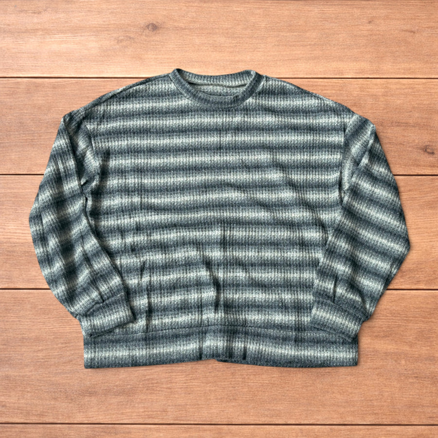 Vintage style knitted sweater jumper with khaki and beige stripes laid flat on wooden surface.
