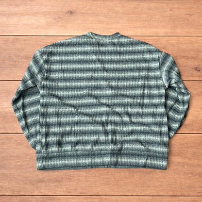 Vintage style knitted sweater jumper with khaki and beige stripes laid flat on wooden surface.
